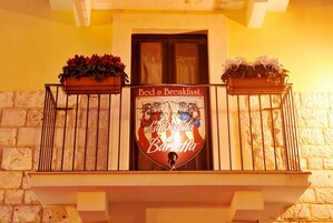 Uma varanda com uma placa que diz "Bed & Breakfast La Disfida di Barveffa" e dois cachepots de flores.