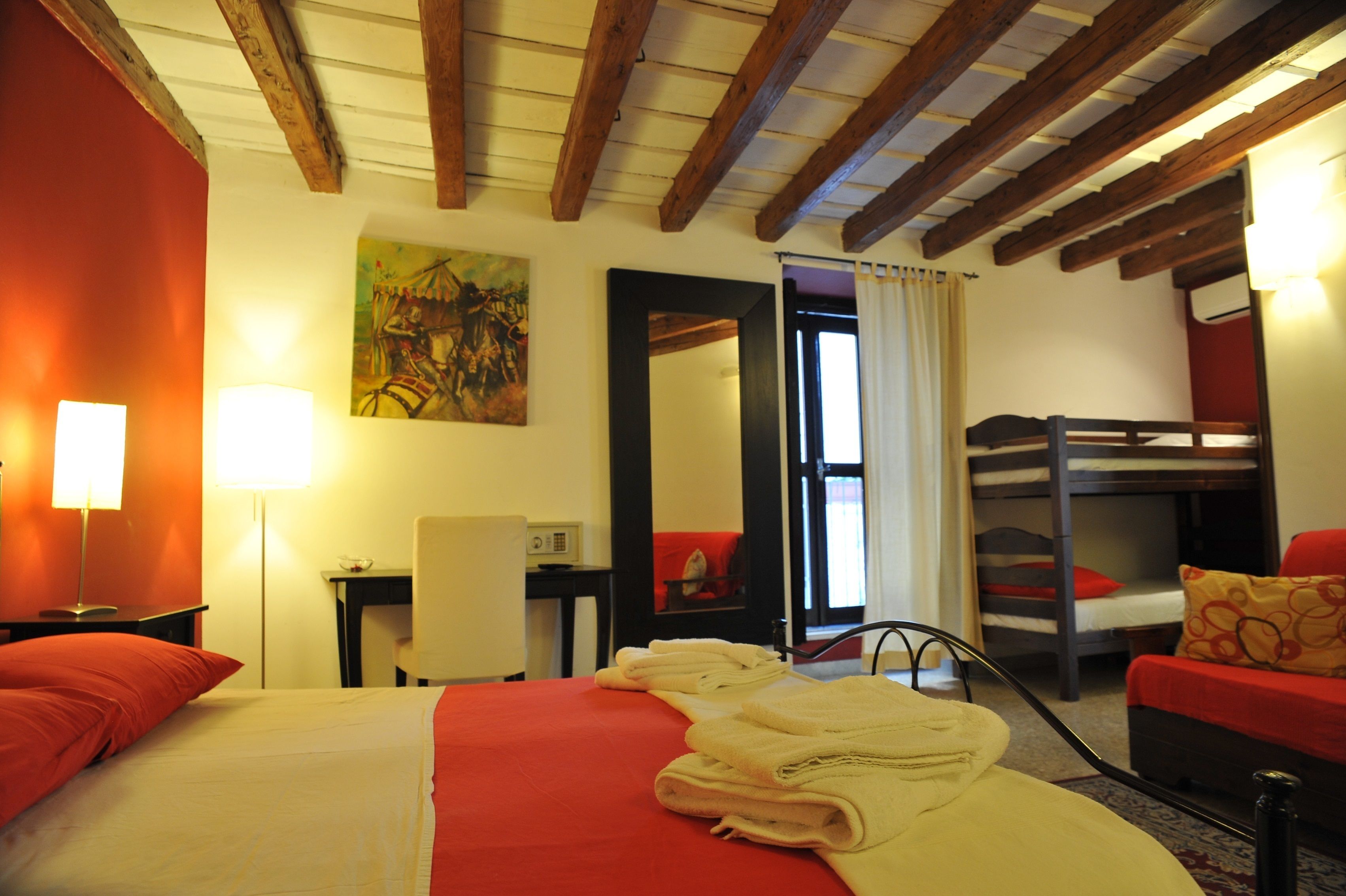 Une chambre d’hôtel avec un lit, un bureau, une chaise, un lit superposé et un tableau au mur.