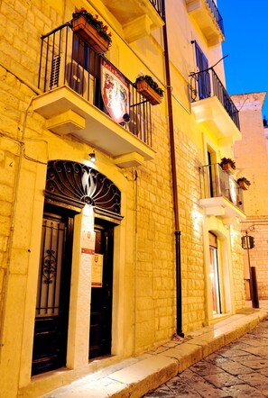 A building with a stone facade, a balcony with a wrought iron railing, and a sign above the entrance. - La Disfida di Barletta (Barletta)