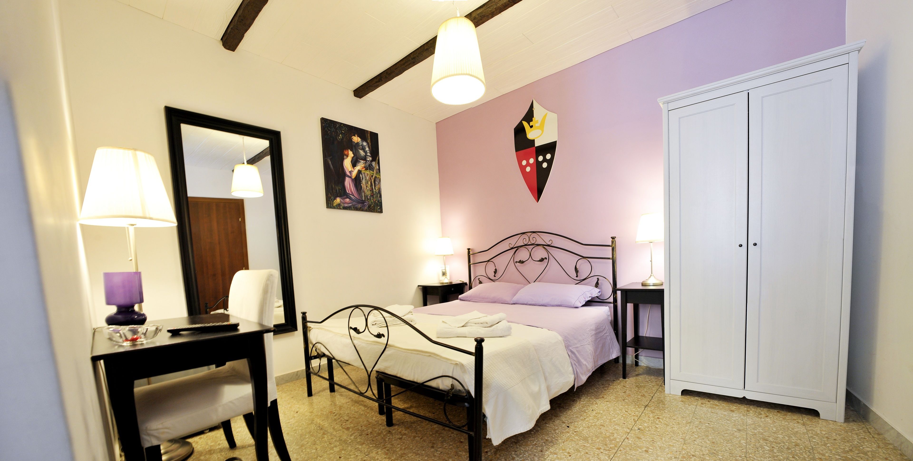 A bedroom with a bed, bedside tables, a desk, a chair, a wardrobe, and a mirror.