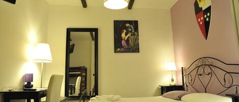 A hotel room with a bed, two bedside tables with lamps, a chair, a mirror, and a wall-mounted artwork.