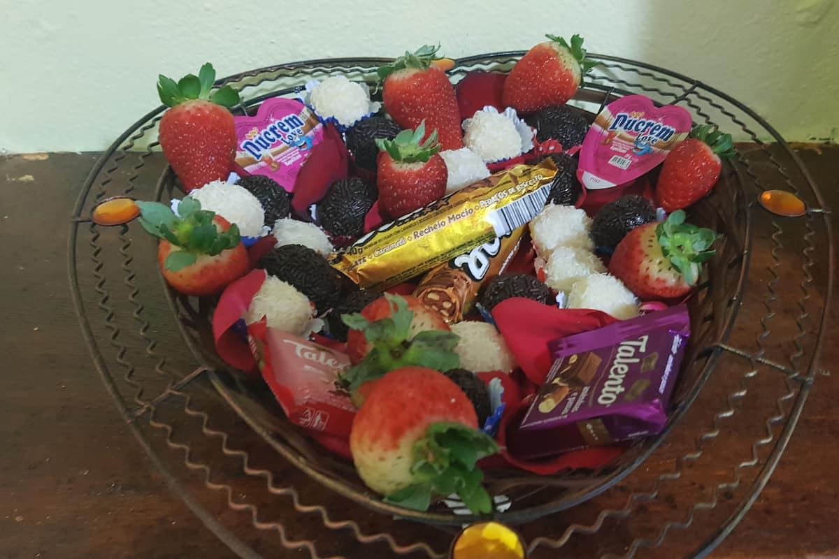 A basket filled with strawberries, chocolate, and various candies.