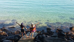 Dos personas de pie sobre rocas junto a un cuerpo de agua claro.