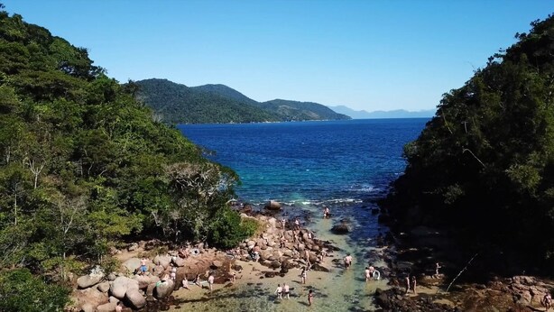 Zona costera con terreno rocoso y agua azul cristalina.