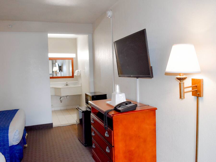 Ett hotellrum med en säng, en byrå, en tv, en lampa och en spegel.