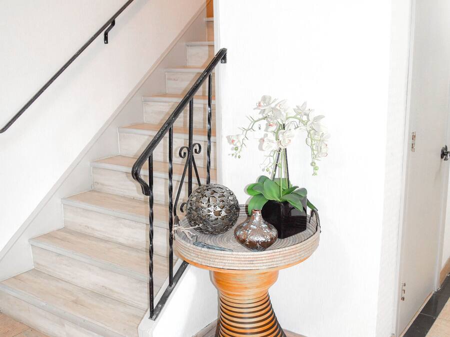 A staircase with a metal railing, a round table with decorative items, and a white door.