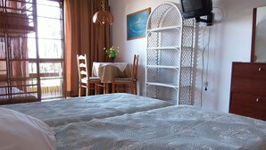 Ein Schlafzimmer mit zwei Betten, einem Schreibtisch mit Stühlen, einem Fernseher und einem Kleiderschrank.