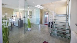 Un interior moderno con una recepción, paredes de cristal, una escalera y una planta en maceta.