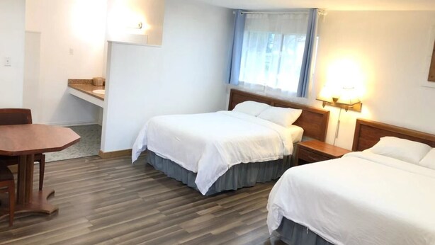 A hotel room with two beds, a desk, and a window with curtains. - Gulfway Motel & Restaurant (High Island)