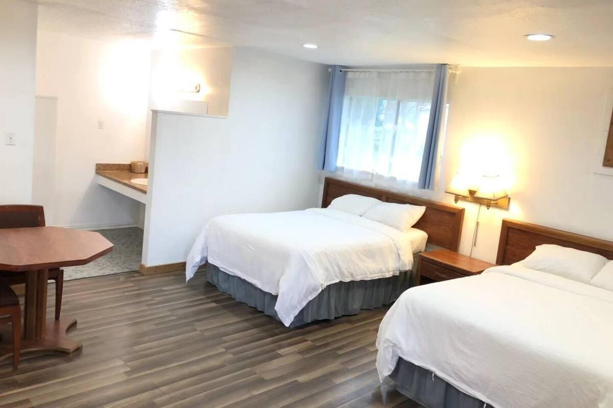 Una habitación de hotel con dos camas, un escritorio y una ventana con cortinas.