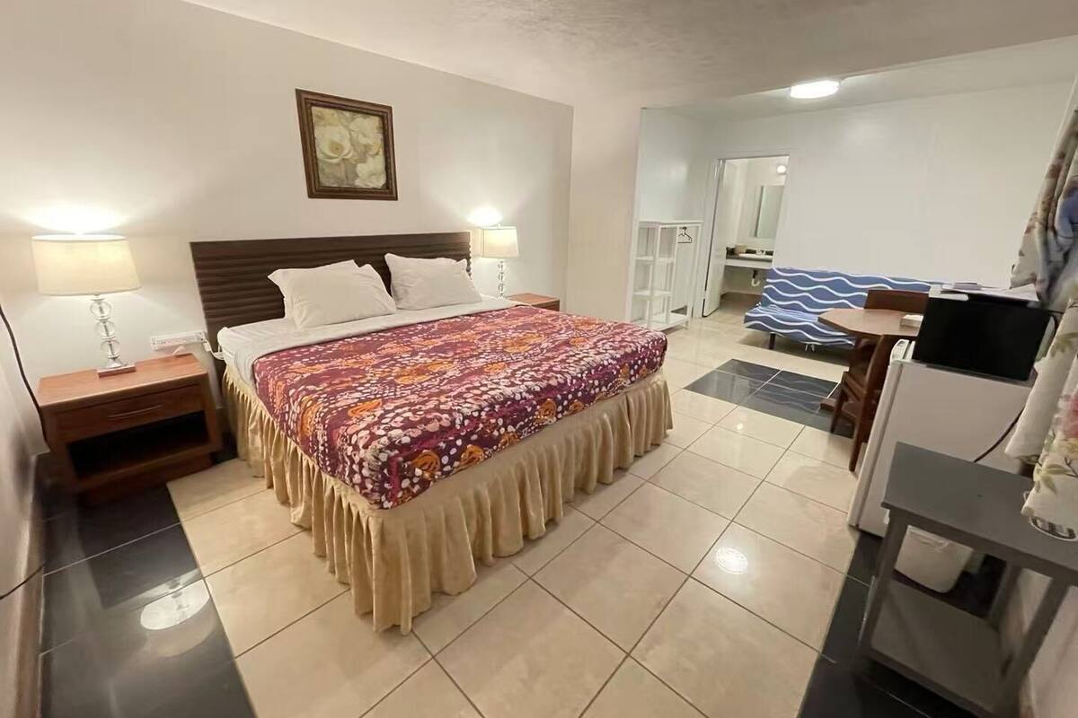 Una habitación de hotel con una cama, mesitas de noche, un escritorio y una silla.