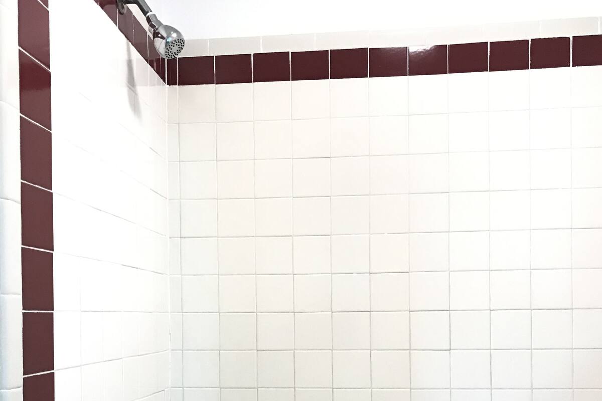 Un baño con una bañera blanca, grifería cromada y paredes de azulejos rojos.