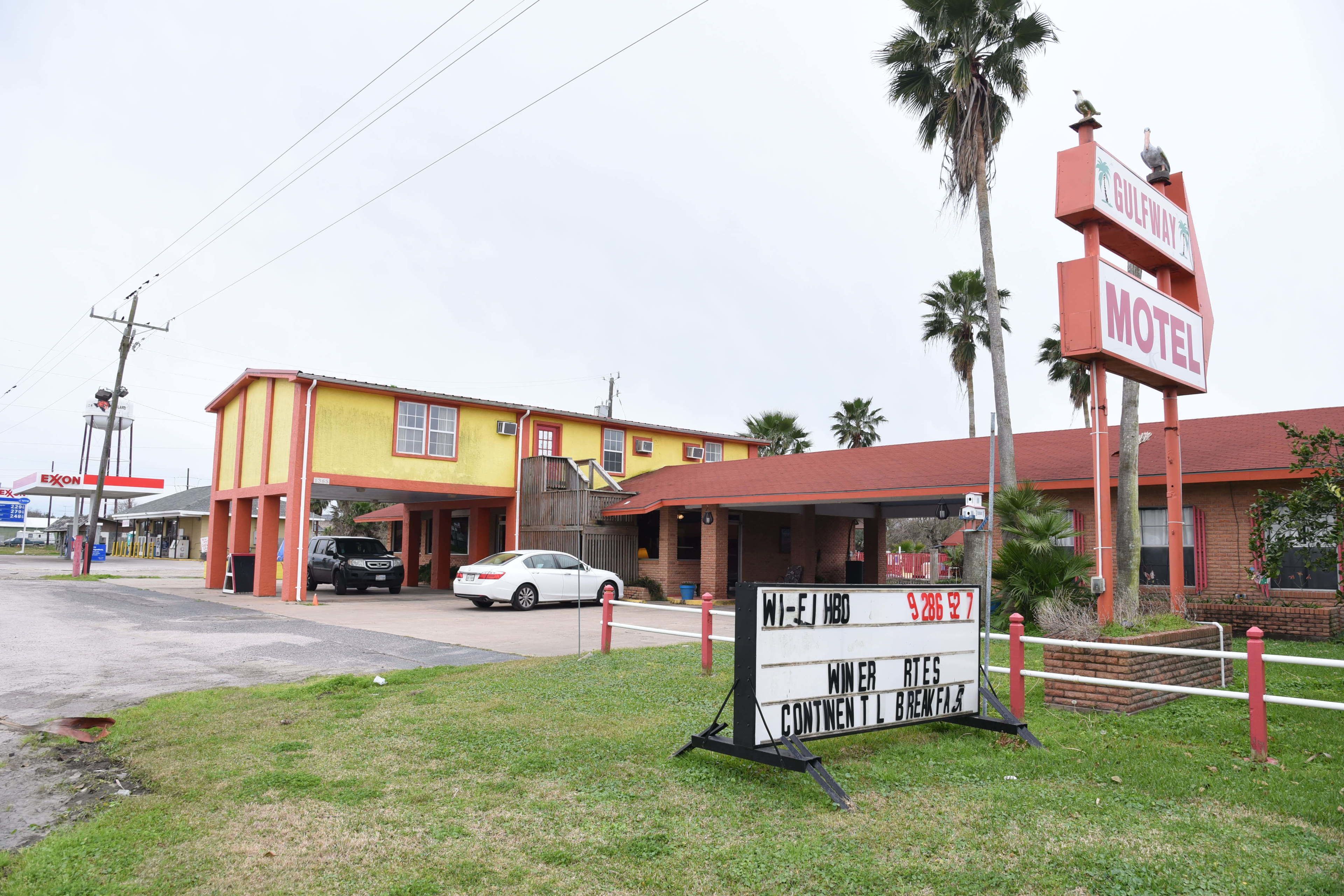 A motel with a yellow facade, a signboard for Wi-EJ HBO, and a visible Exxon gas station in the background.