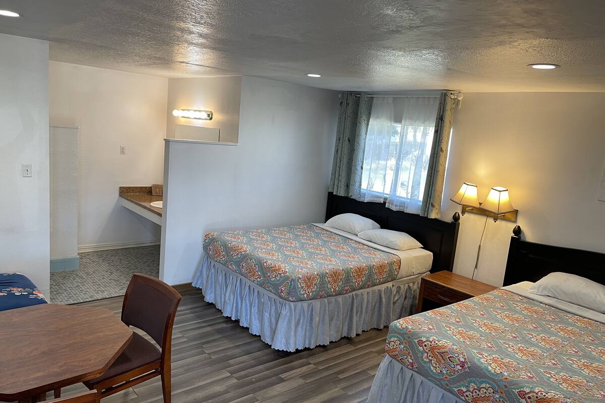 Habitación de hotel con dos camas, una mesita y una silla.