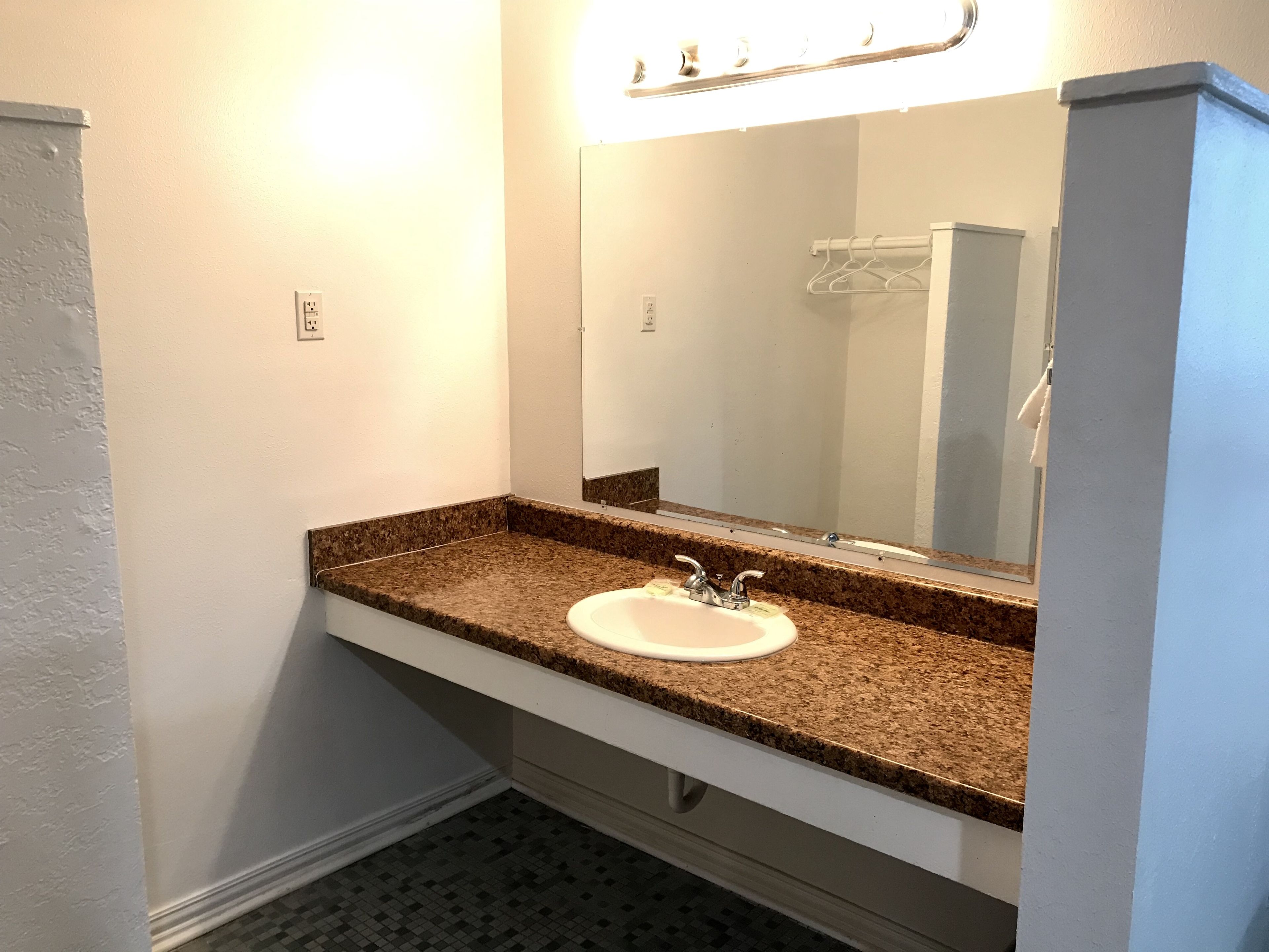 A bathroom with a granite countertop, white sink, and a large mirror.