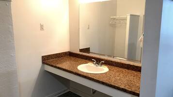 A bathroom with a granite countertop, white sink, and a large mirror.