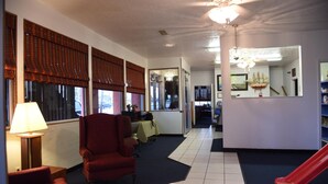 A hotel lobby with a red armchair, a table with a lamp, and a red slide. - Gulfway Motel & Restaurant (High Island)