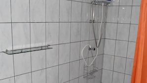 A bathroom with a toilet, a shower, and a towel rack. - Aspid Apartments (Oranjestad)