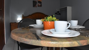 A dining table with white plates, cups, and a fork. There is a potted plant on the table. - Aspid Apartments (Oranjestad)