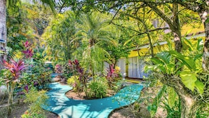 A lush garden with a winding path, surrounded by diverse tropical plants and trees. - Villas Verdes (Sámara)
