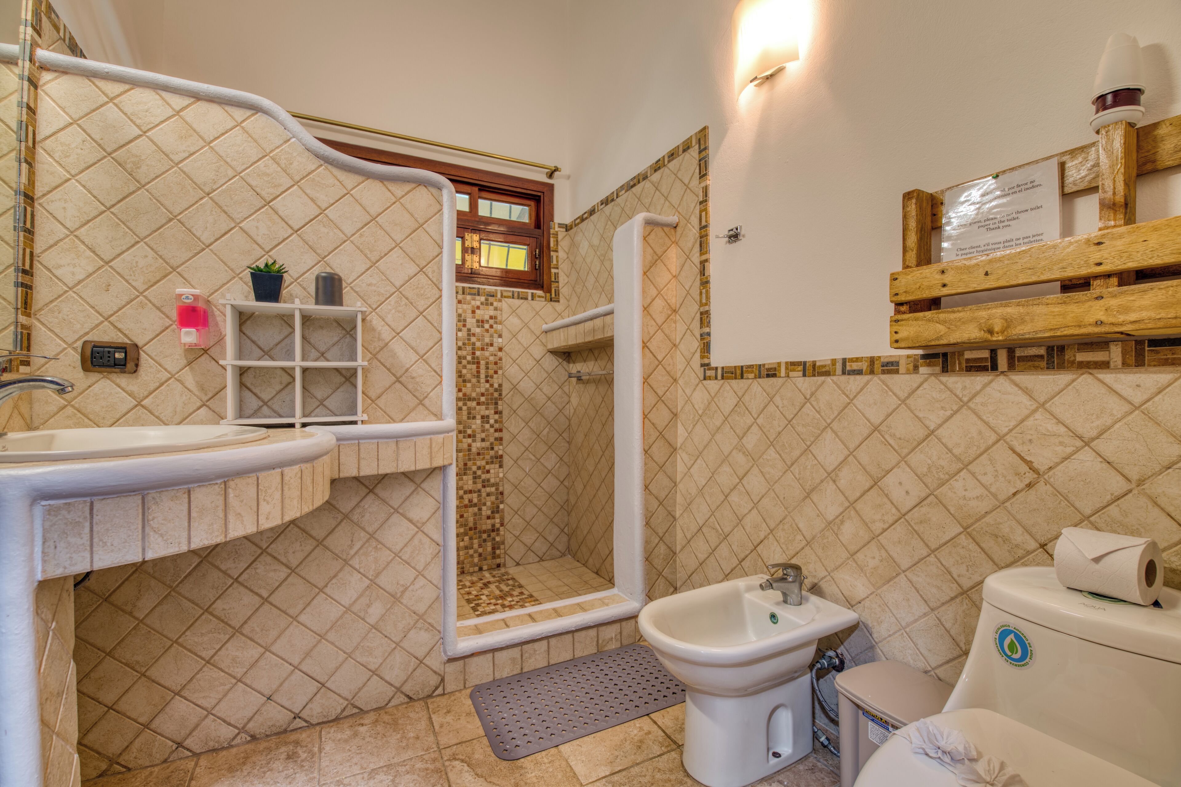 A bathroom with a shower, sink, bidet, and toilet.