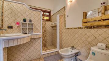 A bathroom with a shower, sink, bidet, and toilet.