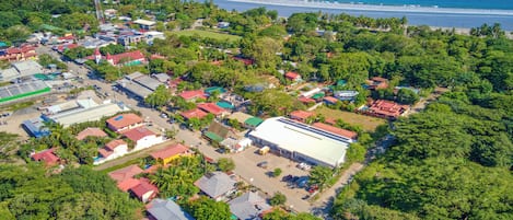 Luftaufnahme einer Küstenstadt mit einer Mischung aus Wohn- und Geschäftsgebäuden, einem großen weißen Lagerhaus und einem gewundenen Strand.