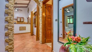 A hallway with stone arches, wooden doors, and a tiled floor. - Villas Verdes (Sámara)