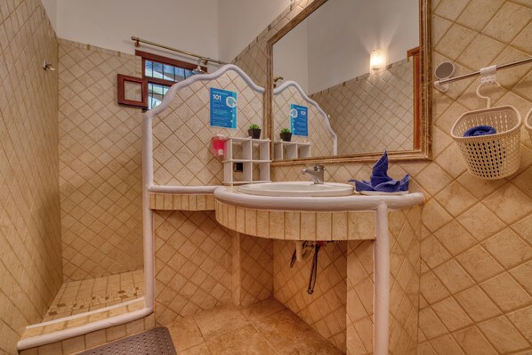 Une salle de bain équipée d’un lavabo, d’un miroir et d’une zone douche.