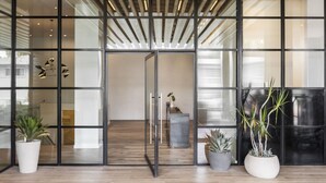 Um interior moderno com portas de vidro, piso de madeira e plantas em vasos.