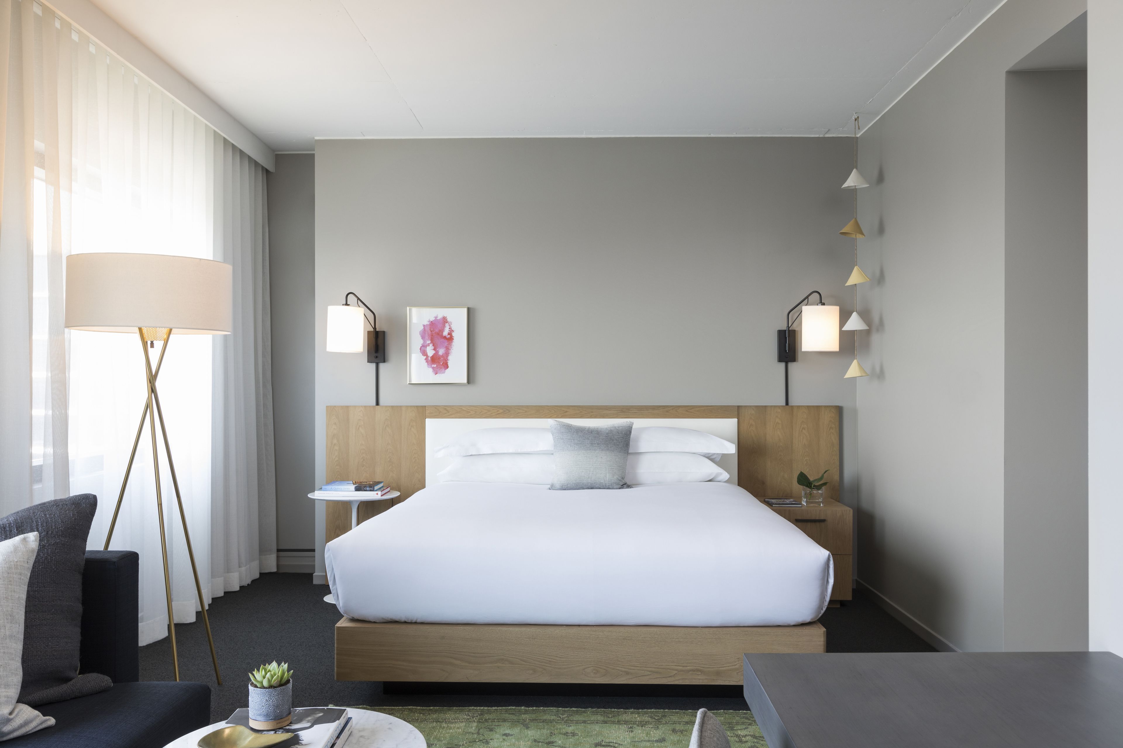 Une chambre d’hôtel avec un grand lit, des tables de chevet, un bureau, une lampe et une plante en pot.