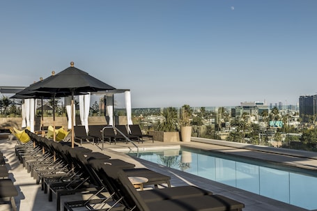 Una piscina al aire libre, camas de piscina con cargo, sombrillas