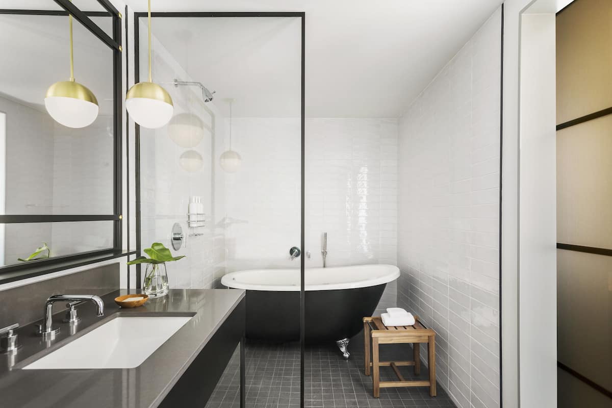 A modern bathroom with a freestanding bathtub, a large mirror, and a sink with a faucet.