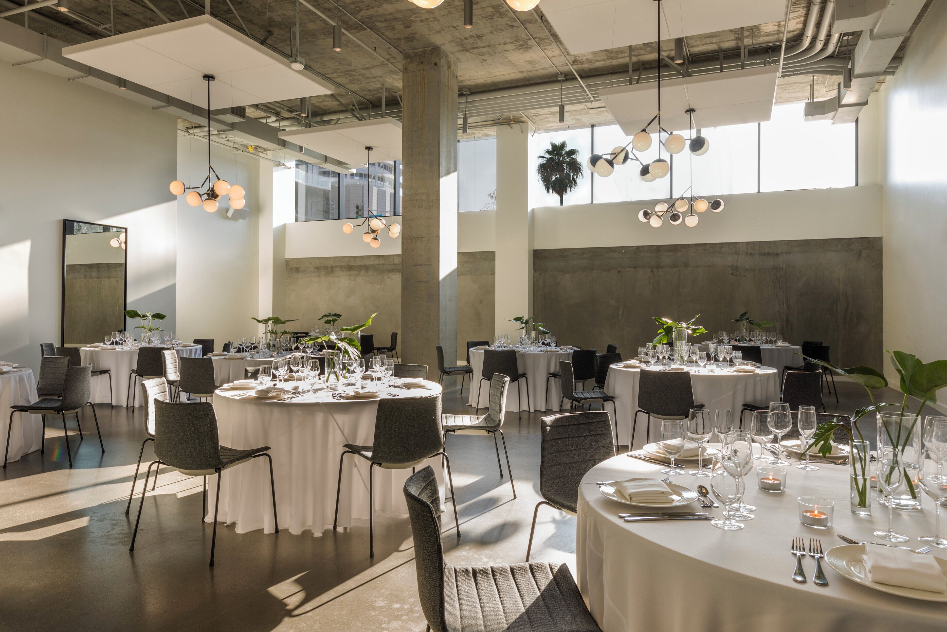 A spacious dining area with round tables, chairs, and modern lighting fixtures.
