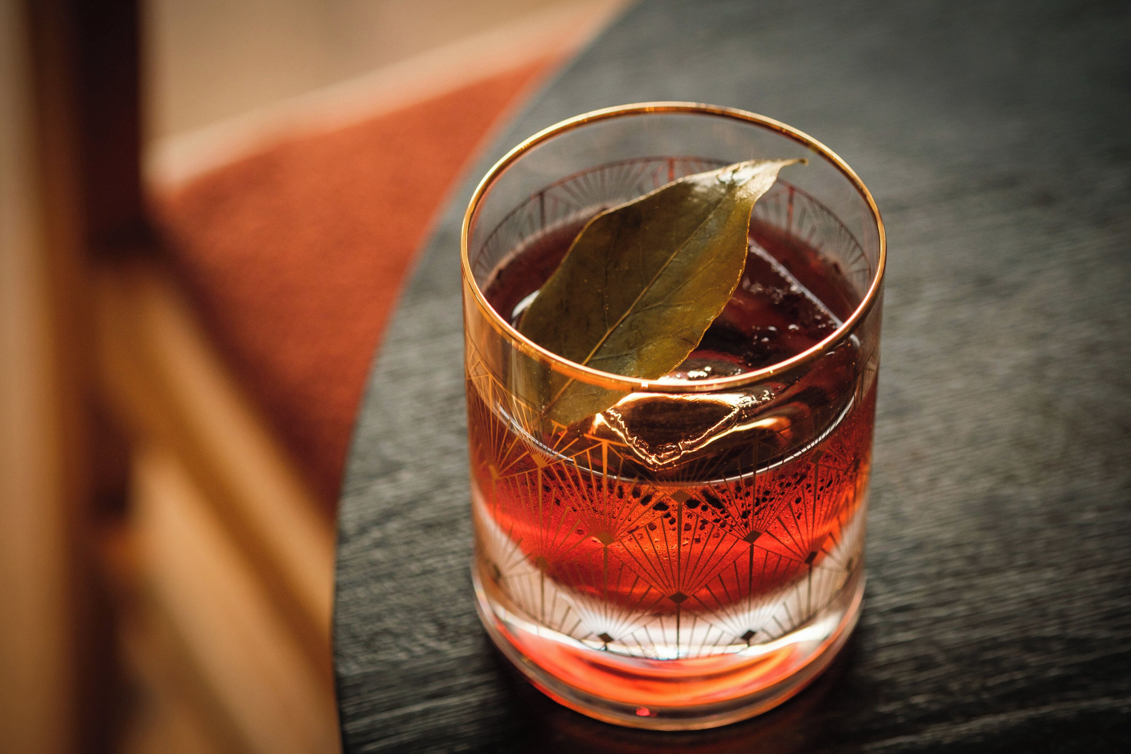 Ein Glas mit einem Lorbeerblatt auf dunklem Untergrund.