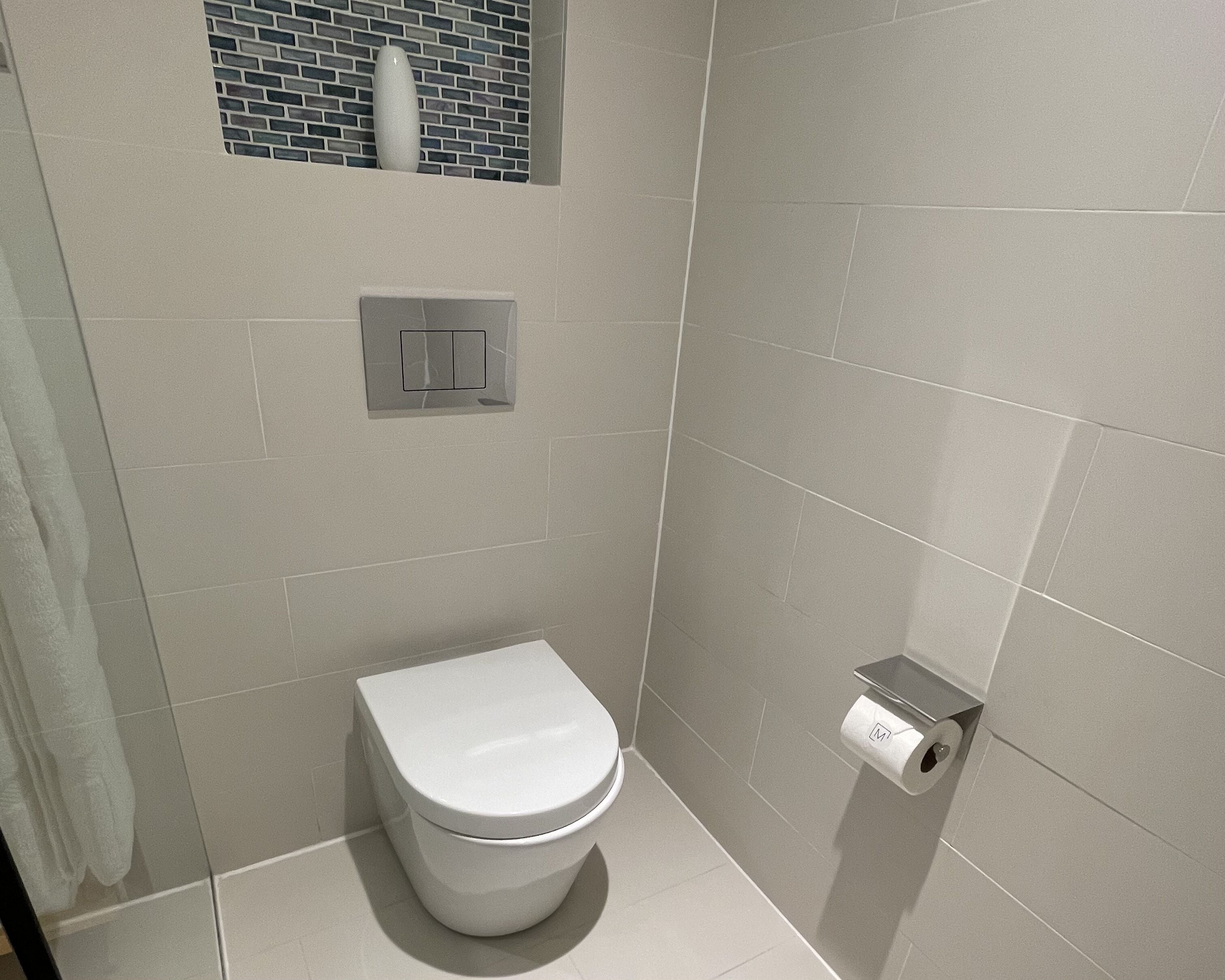 A modern bathroom with a toilet, a towel rack, and a toilet paper holder.
