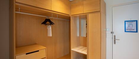 A walk-in closet with wooden cabinetry, a hanging rack, and a white door with a blue emergency plan sign.