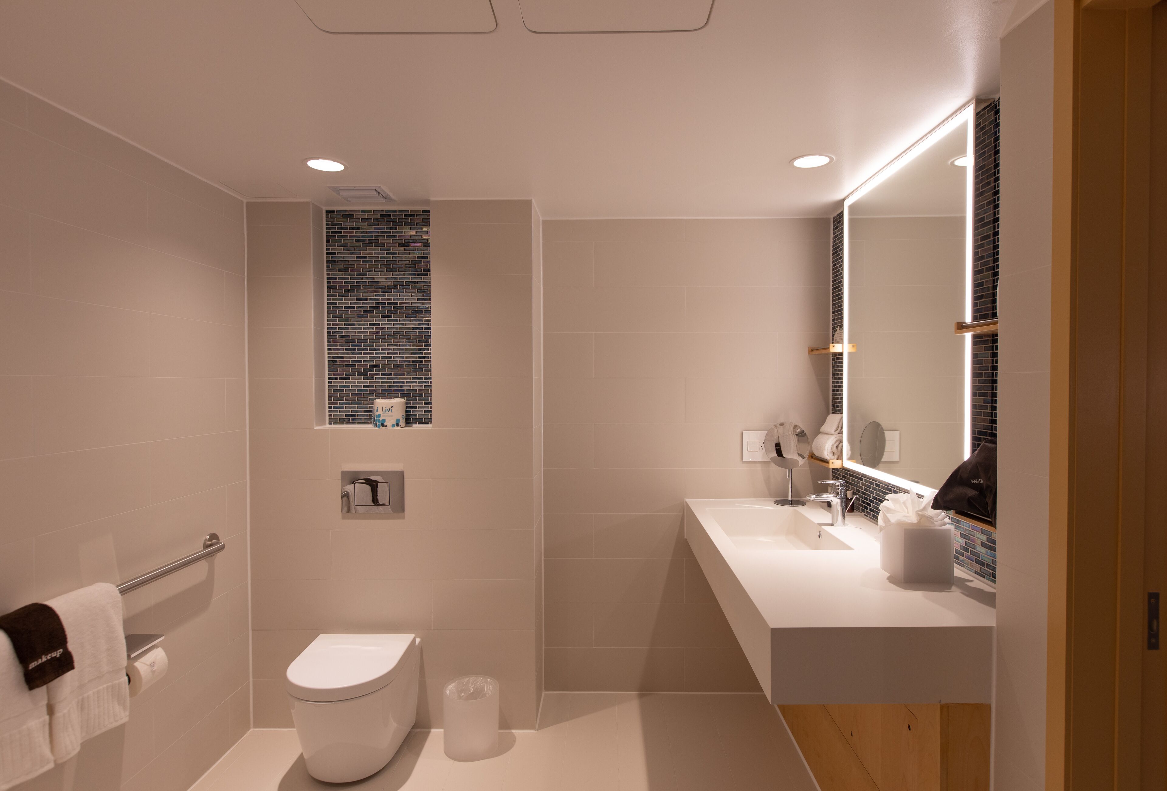 A modern bathroom with a toilet, sink, and mirror.