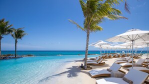 A beachside resort with clear turquoise waters, white sand, and lounge chairs under umbrellas. - The Morgan Resort Spa Village (Simpson Bay)