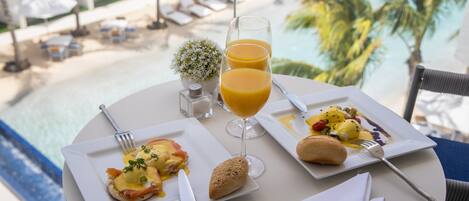 Une table à manger avec des assiettes pour le petit-déjeuner, un verre de jus d’orange et une serviette.