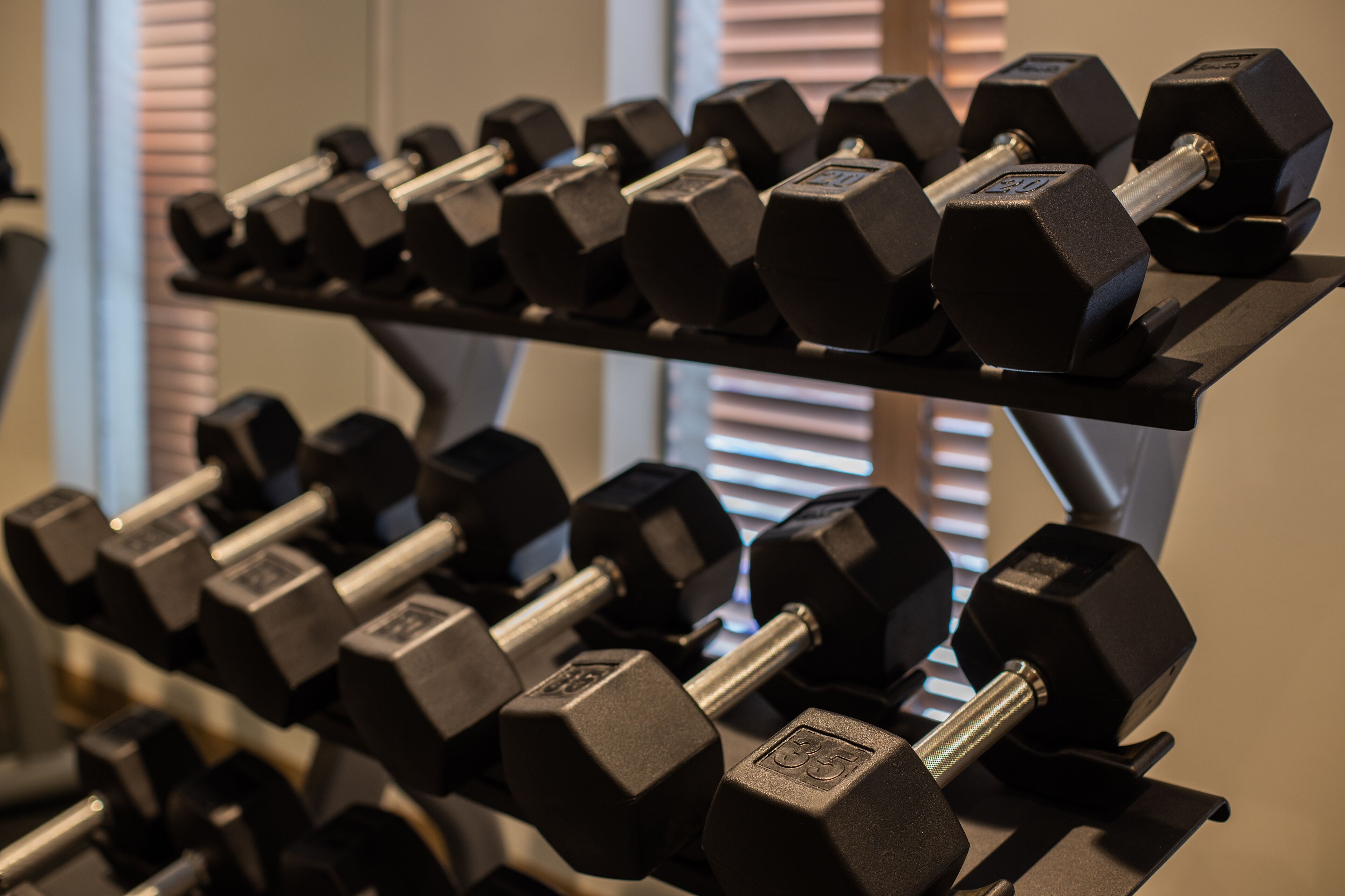 A rack of black dumbbells with weight markings, arranged on a stand.