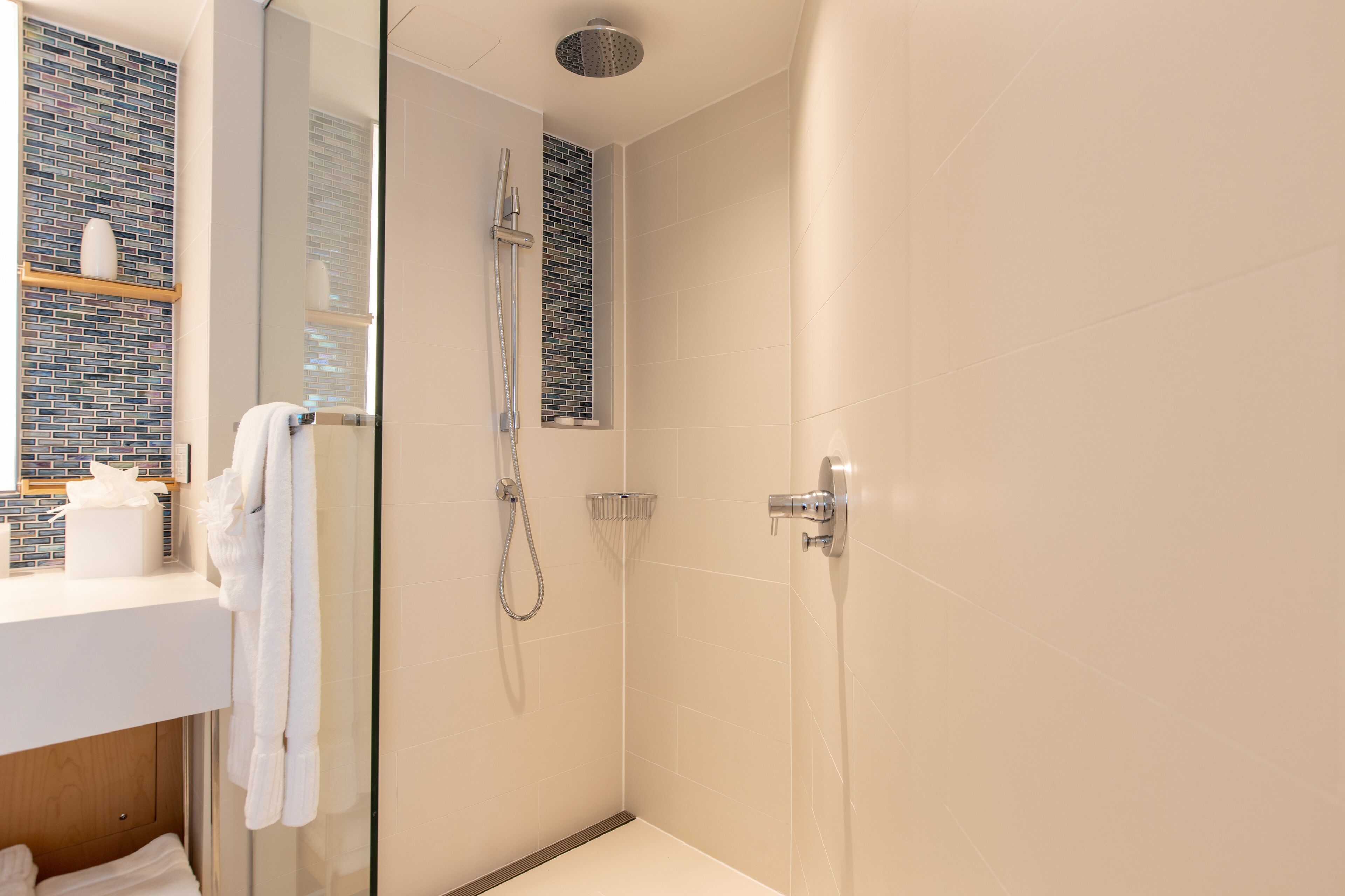 A modern bathroom with a glass shower enclosure, a white sink with a mirror, and a towel rack.
