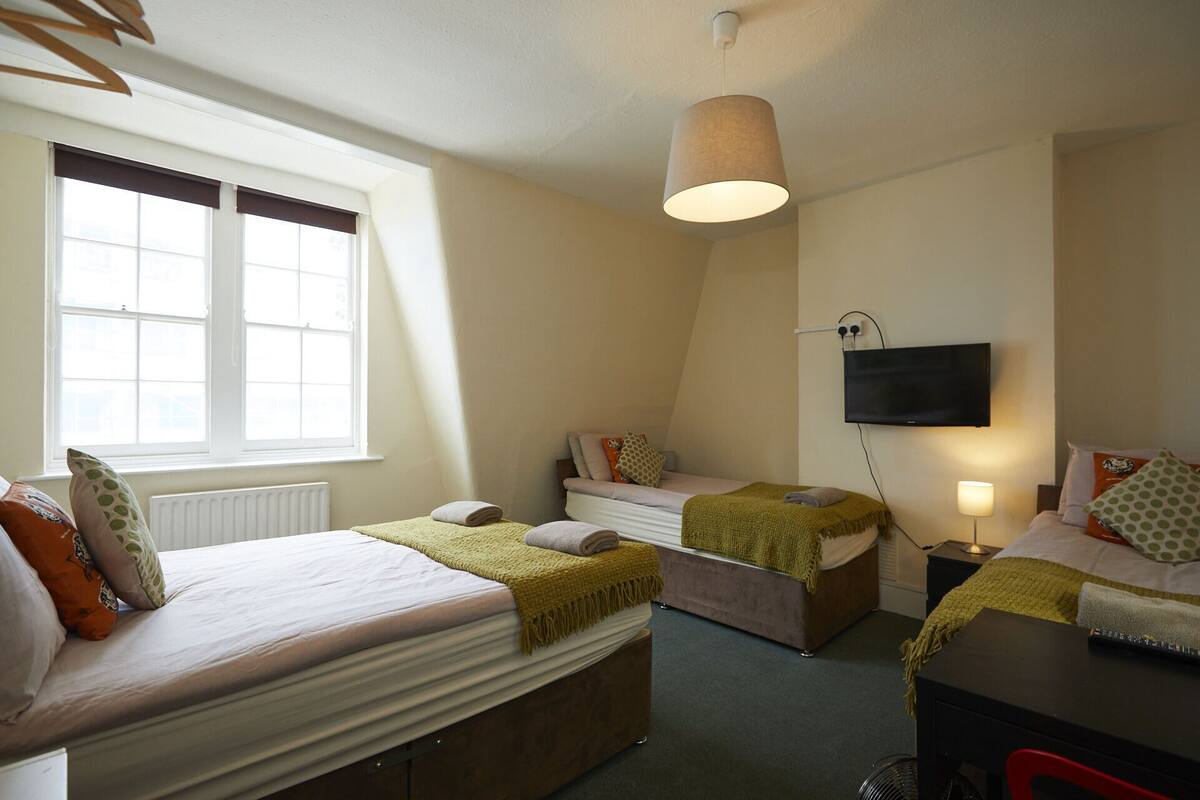 A bedroom with two beds, a TV, and a desk.