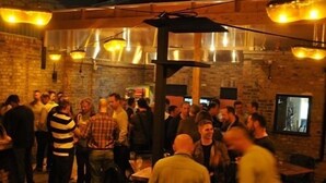 A crowded outdoor dining area with brick walls and hanging lights. - The Grange Pub (London)