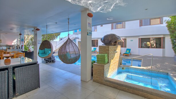 Un espace piscine intérieur moderne, doté d’un fauteuil suspendu, d’un petit bassin et d’un coin salon offrant une vue sur la piscine.
