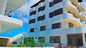 Un hôtel à plusieurs étages doté de balcons, d’une piscine et de vélos garés à l’extérieur.