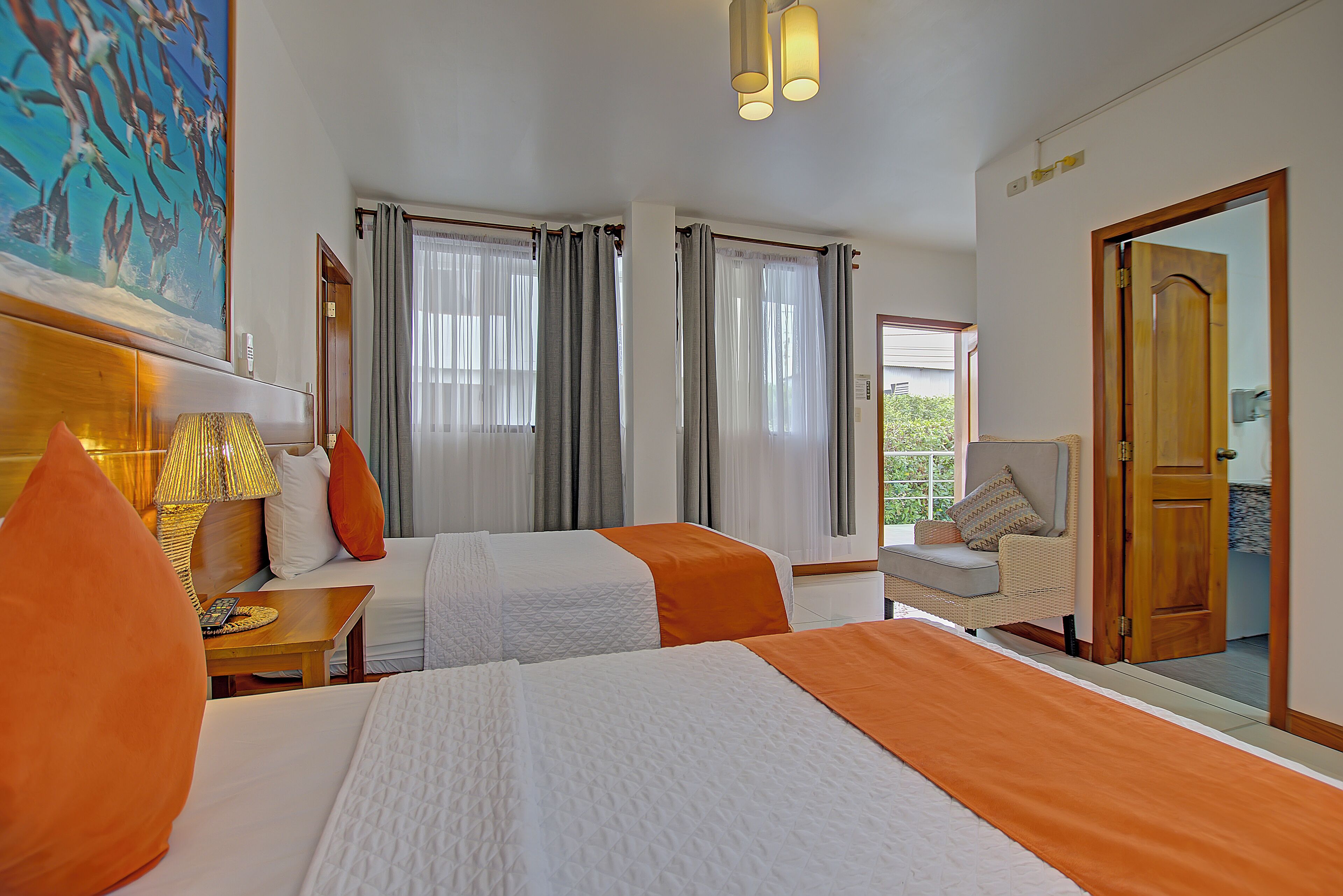 Habitación de hotel con dos camas, una zona de estar y un ventanal con cortinas.