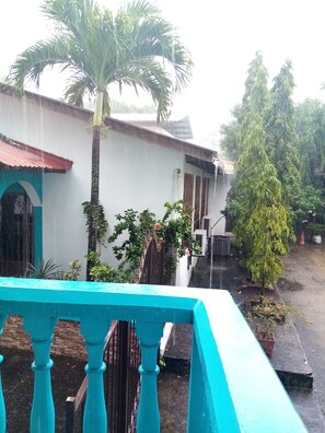Un patio con un edificio blanco, una palmera y una barandilla azul.