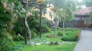 A garden with a pergola, palm trees, and a pathway. - Hotel Molina (La Ceiba)