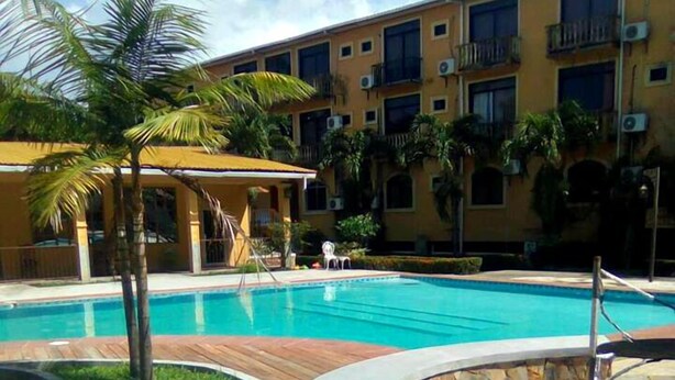 A swimming pool with a stone fire pit, surrounded by a tiled deck and palm trees. - Hotel Molina (La Ceiba)